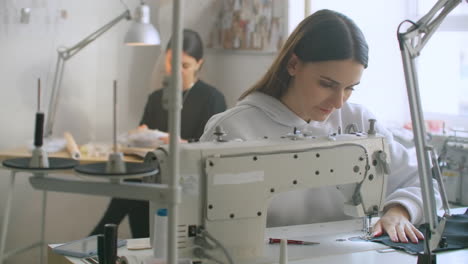 Dressmaker-sewing-clothes.-Fashion-designer-sewing-new-model-of-clothes.-Seamstress-woman-works-on-sewing-machine-in-tailoring-workshop-business.-She-stitches-details-for-future-clothing.